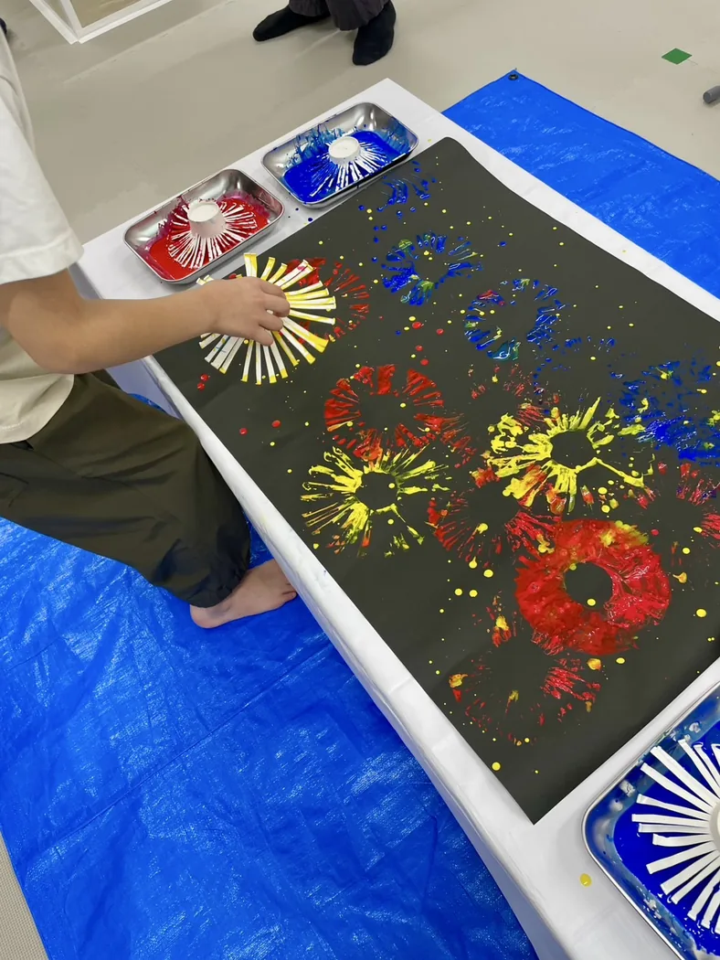 黒い紙に色を重ねて創作している様子