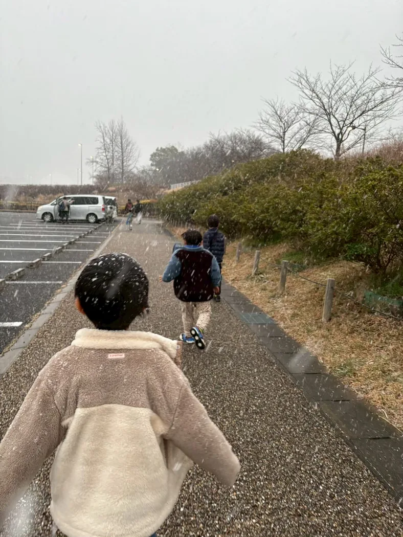 雪の中を前へ歩いていく子どもたちの後ろ姿