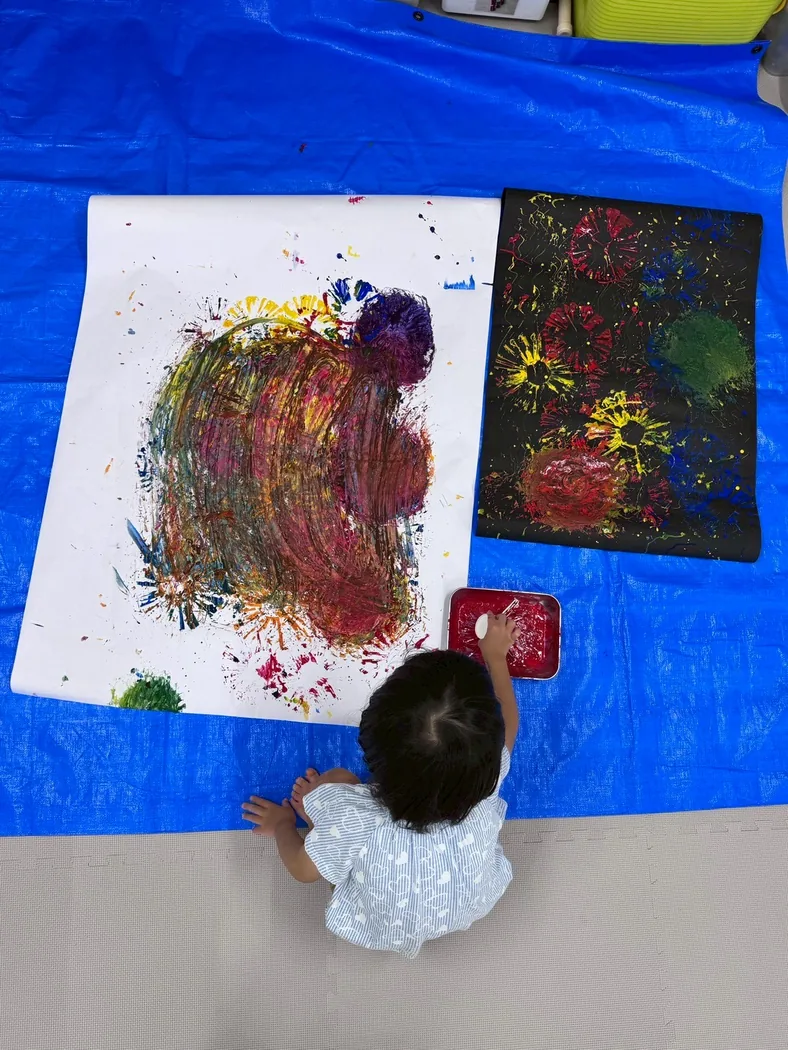 大きな紙に絵の具で創作する子ども